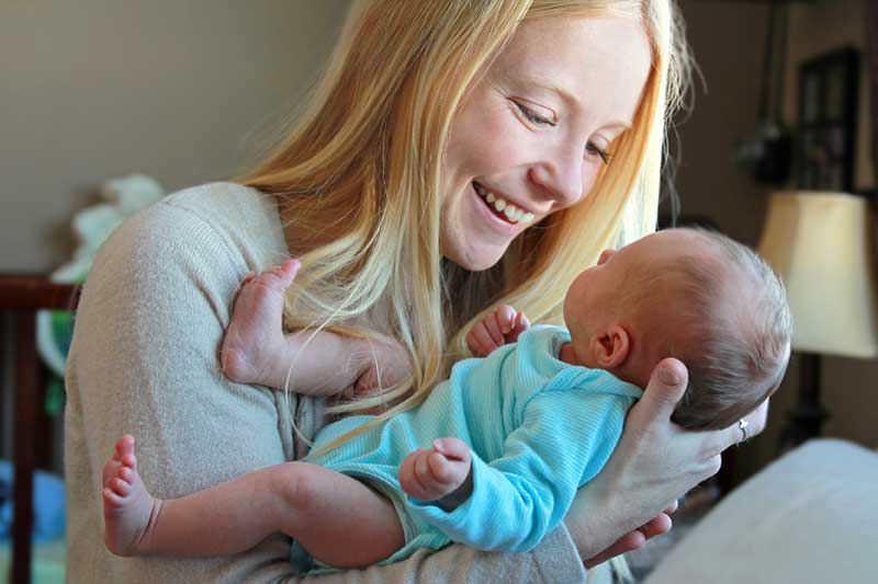 A mother smiles as she cradles her newborn infant.